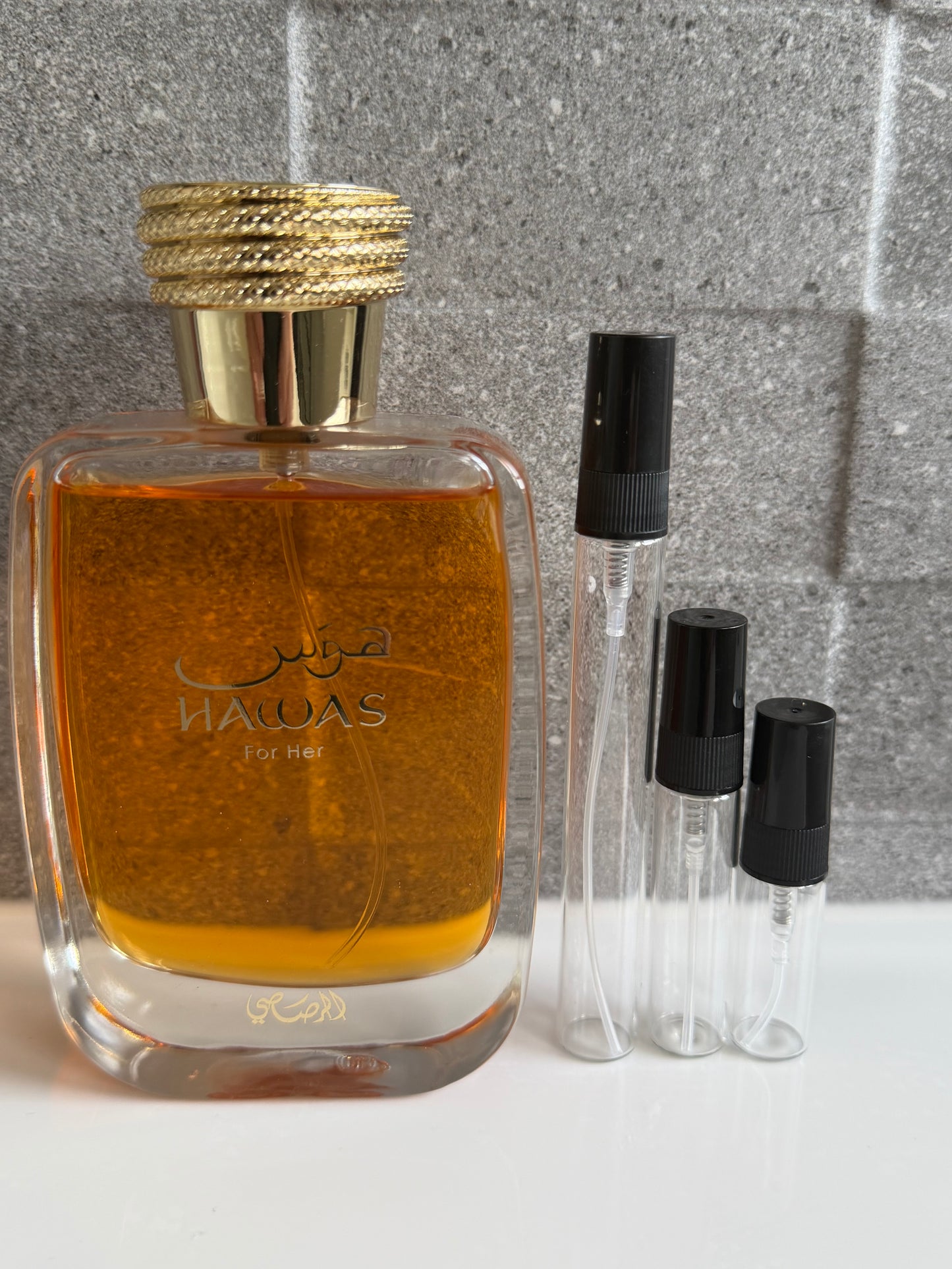 Perfume bottle with gold cap and black caps on a textured surface